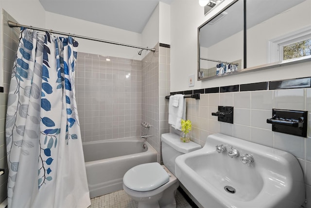 full bath with visible vents, a sink, shower / tub combo, tile walls, and toilet