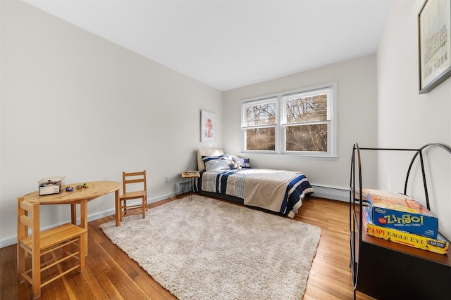 bedroom with baseboards, light wood-style floors, and a baseboard radiator