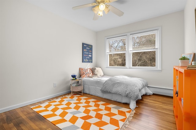 bedroom featuring light wood-type flooring, a baseboard radiator, baseboards, and ceiling fan