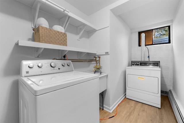 laundry room with a baseboard heating unit, light wood finished floors, baseboards, laundry area, and washing machine and clothes dryer