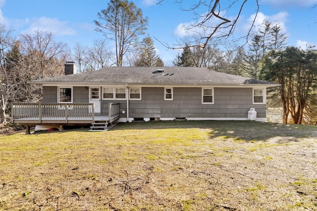 back of property featuring a lawn, roof with shingles, a deck, and a chimney