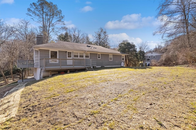 rear view of property with a lawn, a chimney, and a deck