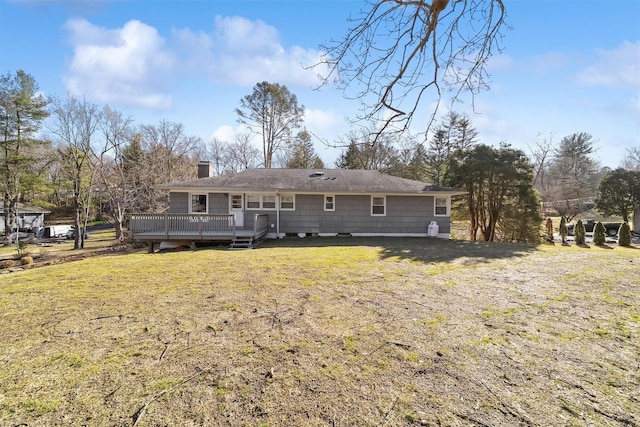 back of property with a lawn, a chimney, and a wooden deck