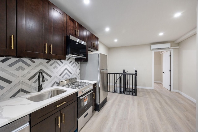 kitchen featuring appliances with stainless steel finishes, sink, a wall mounted AC, light stone countertops, and light wood-type flooring