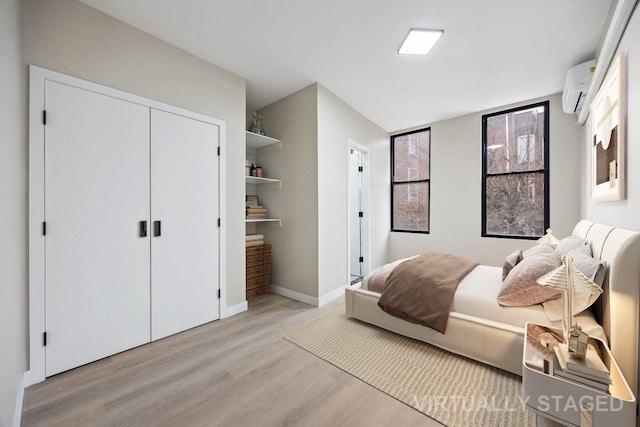 bedroom with a wall unit AC, a closet, and light wood-type flooring