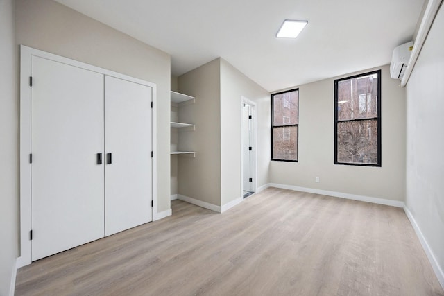 unfurnished bedroom featuring a wall mounted air conditioner, light wood-type flooring, and a closet