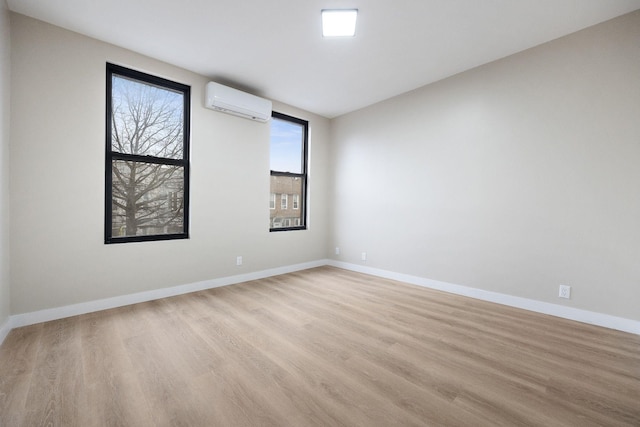 empty room with light hardwood / wood-style floors and an AC wall unit