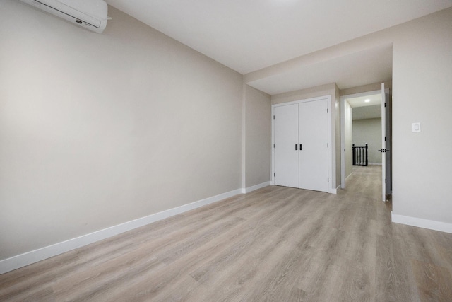 empty room featuring an AC wall unit and light wood-type flooring