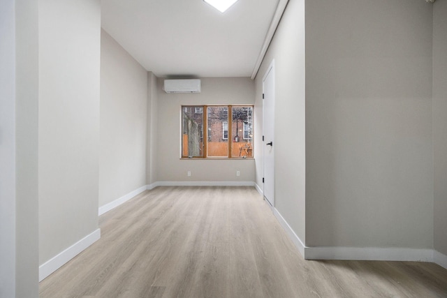 spare room featuring a wall unit AC and light hardwood / wood-style flooring