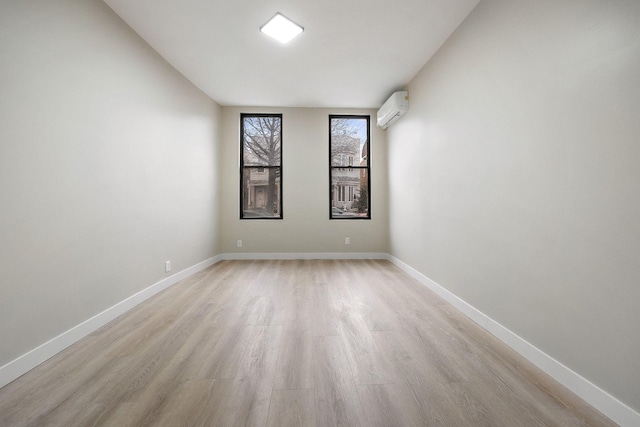 spare room featuring an AC wall unit and light wood-type flooring