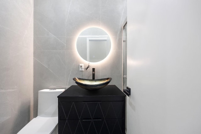 bathroom featuring tile walls, vanity, and toilet