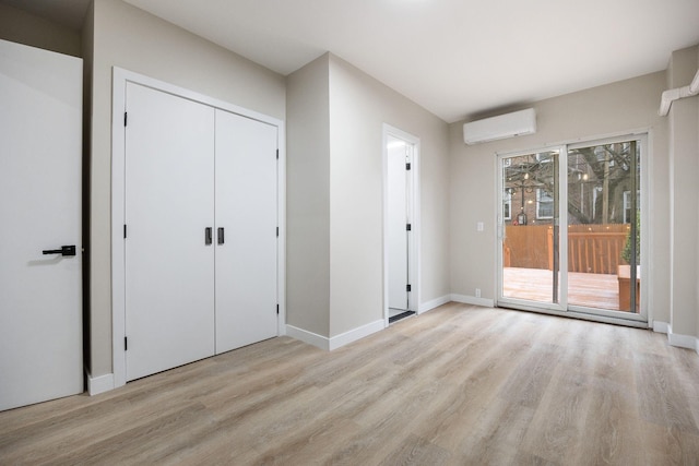 unfurnished bedroom with a wall mounted air conditioner, access to exterior, and light wood-type flooring