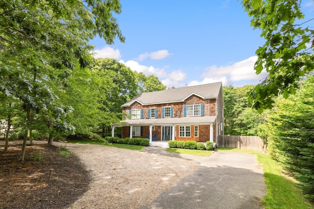 view of front of house with driveway, a chimney, and fence