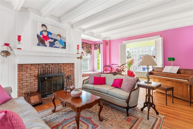 living room featuring a brick fireplace, light wood-type flooring, and beam ceiling