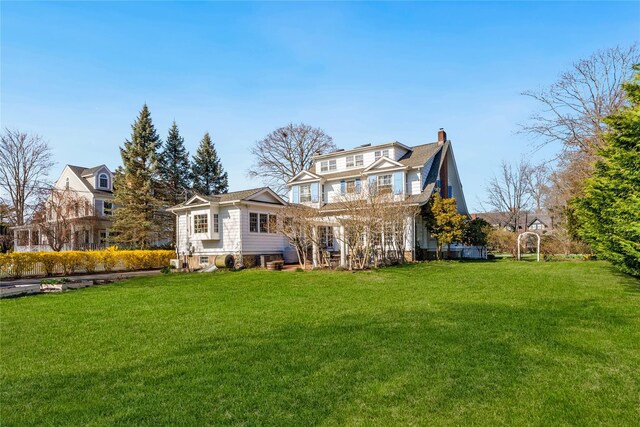 rear view of property with a chimney and a lawn