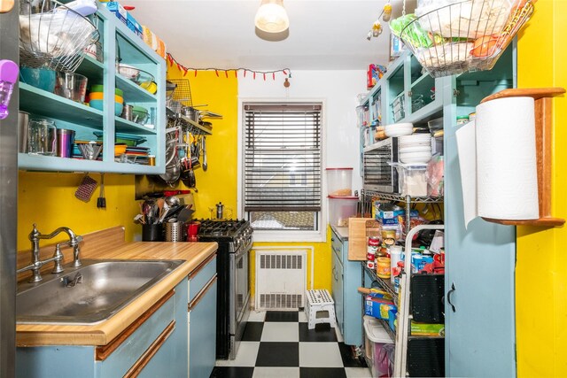 kitchen featuring dark floors, butcher block counters, a sink, open shelves, and radiator heating unit