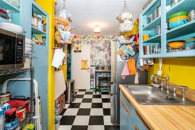 kitchen featuring dark floors, open shelves, a sink, and decorative light fixtures