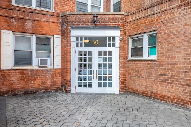 view of exterior entry featuring brick siding, cooling unit, and french doors