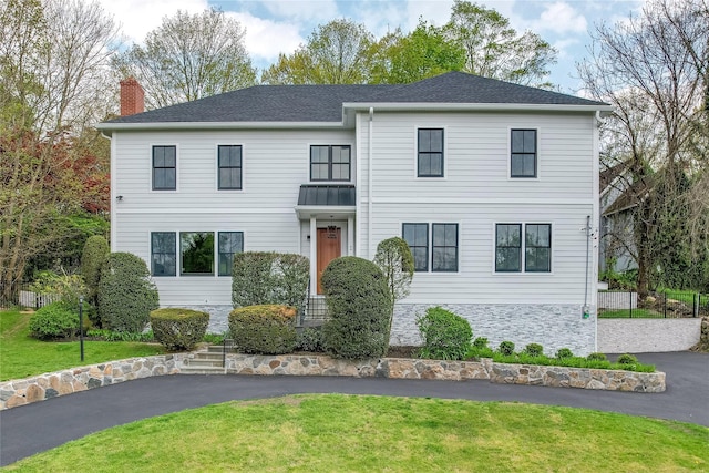 view of front of property with driveway, a shingled roof, a chimney, and a front yard