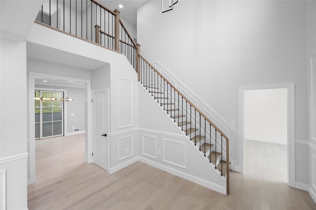 stairway featuring recessed lighting, wood finished floors, a towering ceiling, and baseboards