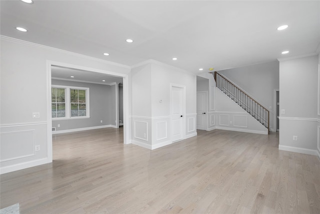 empty room featuring light wood-style flooring, stairway, a decorative wall, and recessed lighting