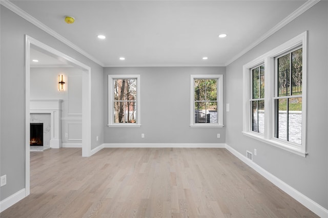 unfurnished living room with ornamental molding, a high end fireplace, and baseboards