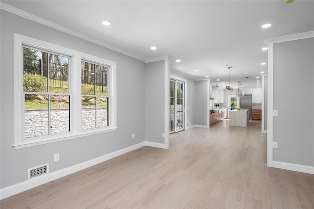 unfurnished room with baseboards, light wood-type flooring, visible vents, and crown molding