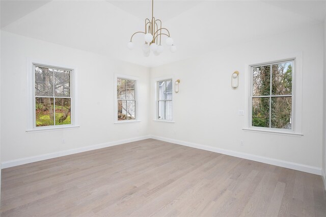 unfurnished room with a healthy amount of sunlight, light wood-style floors, baseboards, and an inviting chandelier