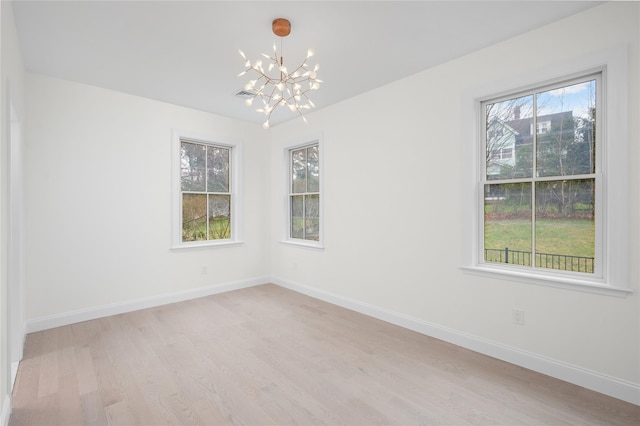 unfurnished room with light wood-style floors, a chandelier, visible vents, and baseboards