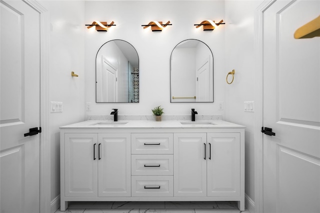 bathroom featuring double vanity, baseboards, and a sink