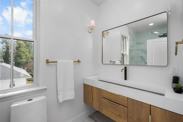 full bath with baseboards, a healthy amount of sunlight, vanity, and a marble finish shower