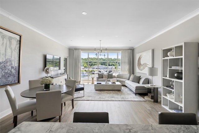 living room featuring an inviting chandelier, ornamental molding, and light wood-type flooring