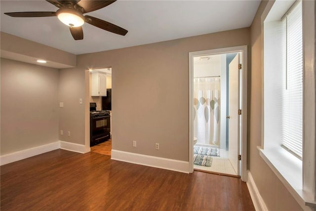 spare room with ceiling fan, dark wood-type flooring, and baseboards