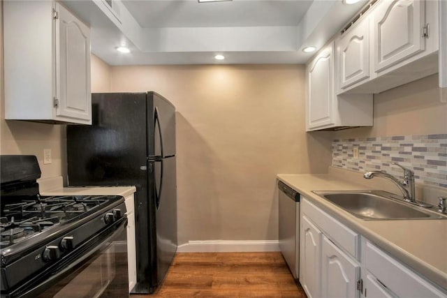 kitchen with wood finished floors, white cabinetry, black appliances, and a sink