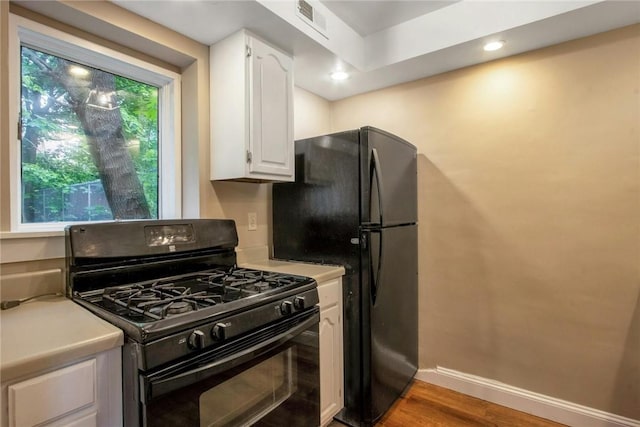 kitchen with white cabinetry, black appliances, light countertops, and baseboards