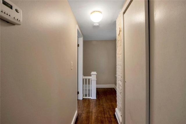 hall featuring dark wood-type flooring, an upstairs landing, and baseboards