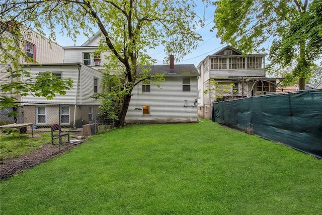 rear view of property with a yard, fence, a sunroom, and a chimney