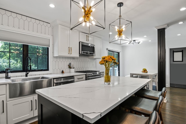 kitchen with stainless steel appliances, a kitchen island, a sink, white cabinetry, and decorative backsplash