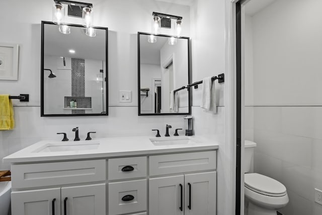 full bathroom with a sink, tile walls, toilet, and double vanity