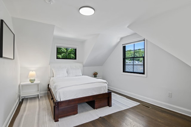 bedroom with visible vents, baseboards, vaulted ceiling, and wood finished floors