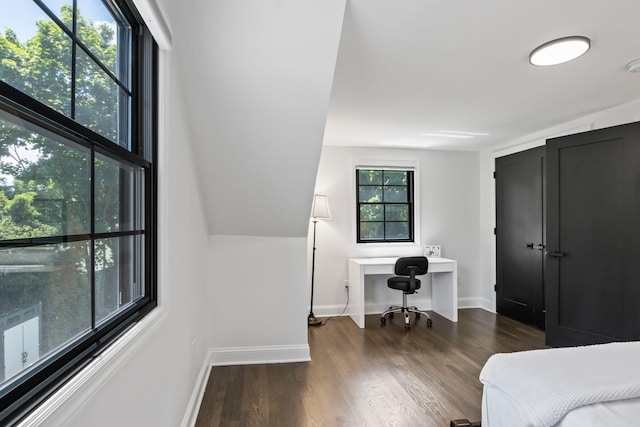 bedroom with wood finished floors, built in study area, and baseboards