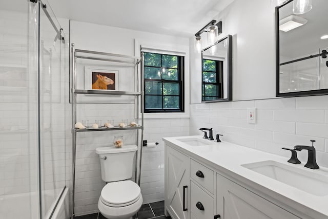 bathroom featuring double vanity, a sink, toilet, and tile walls