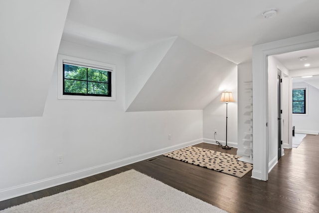 additional living space featuring lofted ceiling, dark wood finished floors, and baseboards