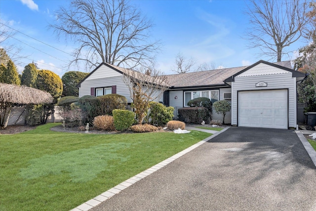 ranch-style home with aphalt driveway, an attached garage, and a front lawn