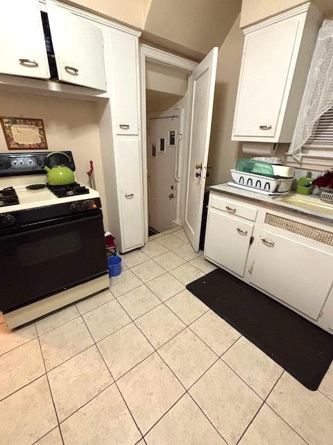 kitchen with range with gas stovetop, light tile patterned floors, and white cabinets