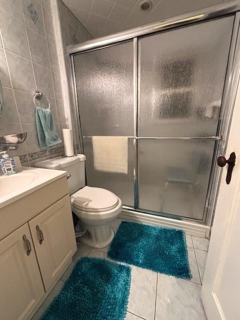 bathroom featuring vanity, an enclosed shower, tile patterned flooring, and tile walls