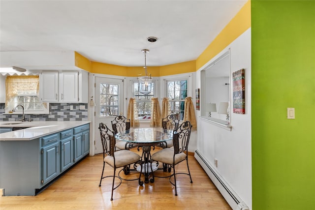 dining room featuring baseboard heating, sink, and light hardwood / wood-style flooring