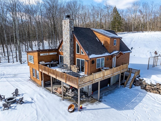 snow covered back of property featuring a wooden deck and an outdoor fire pit