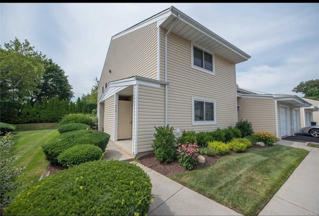 view of side of property featuring a garage and a lawn