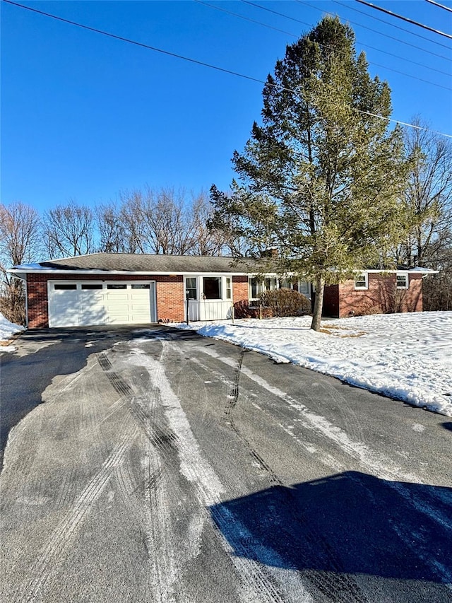 view of front of home featuring aphalt driveway, an attached garage, and brick siding